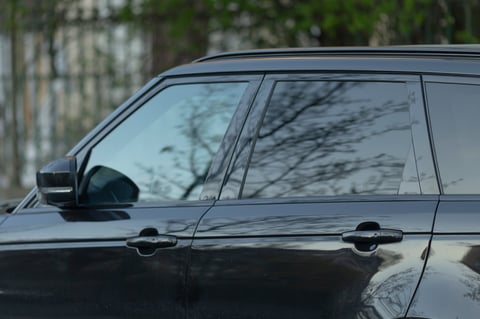 Black luxury SUV detail - glossy polished exterior with reflections